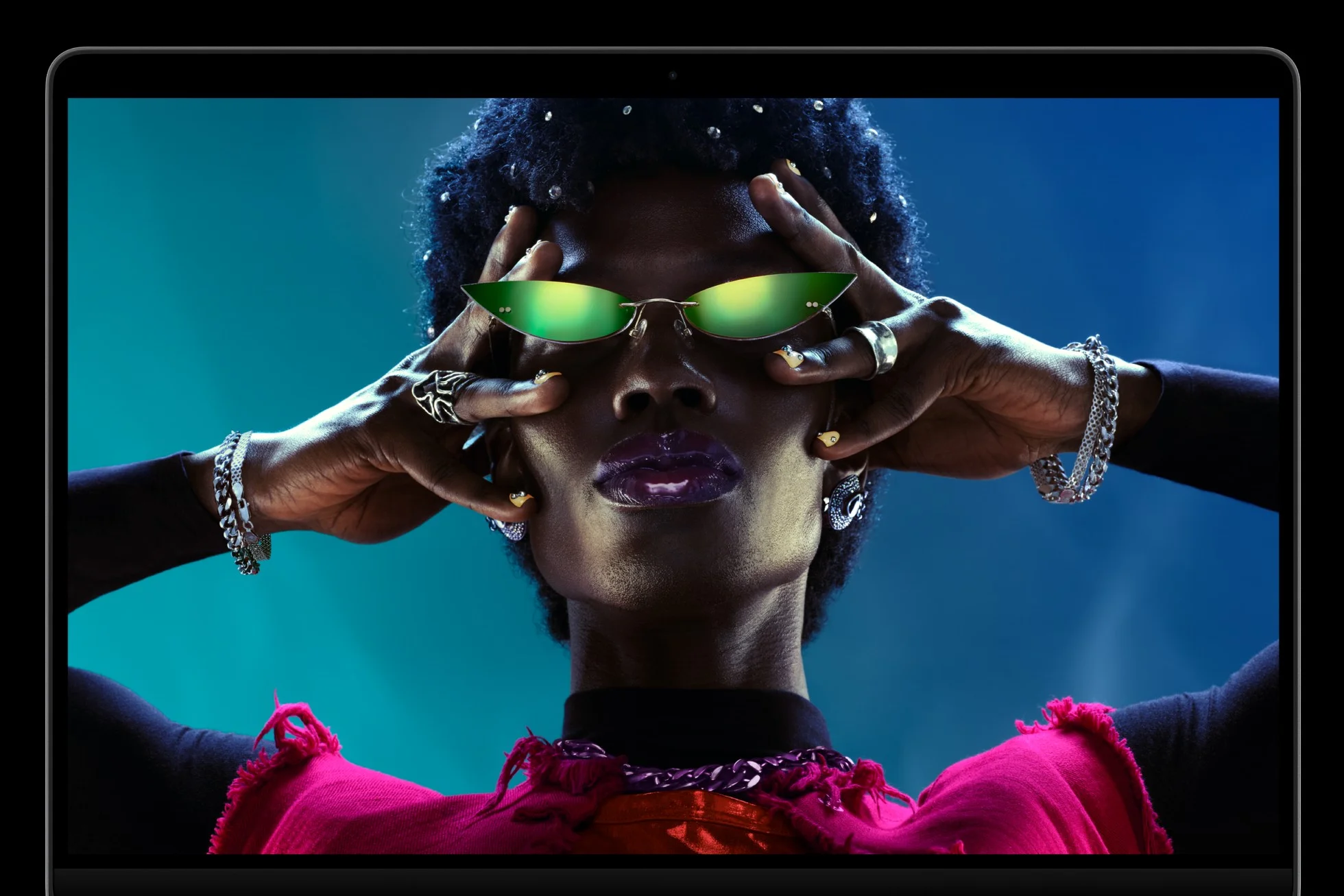 หน้าจอ MacBook Pro แสดงภาพบุคคลสวมแว่นสีเขียวบนพื้นหลังสีฟ้า